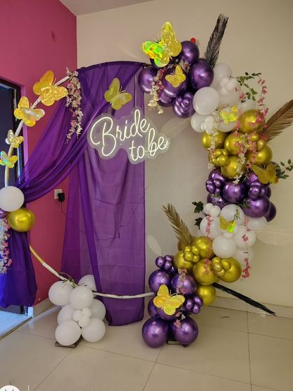 A whimsical 'Bride to be' decoration in purple, gold, and white. I used a circular frame with drapes, a balloon garland, and butterfly accents for a unique look.