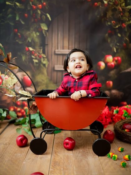 A happy moment in the apple orchard setup. The baby's joyful expression makes this photo extra sweet.