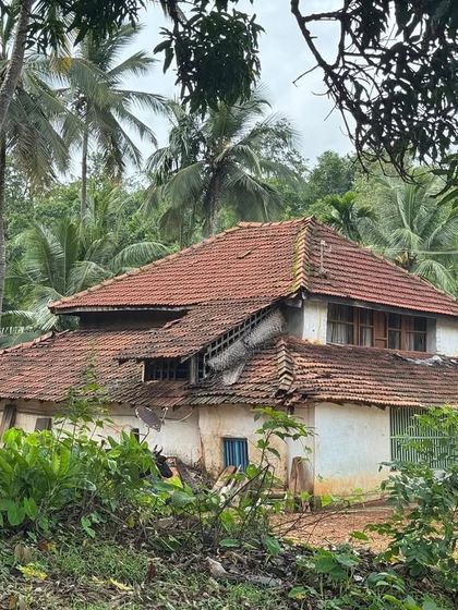 A large, traditional Malnad house with a classic tiled roof, showcasing the unique architecture of the region.