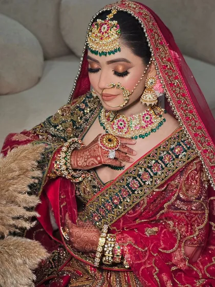 A stunning portrait of a bride in a deep red and green velvet lehenga. The intricate zardozi work and the rich colors are perfect for a winter wedding.