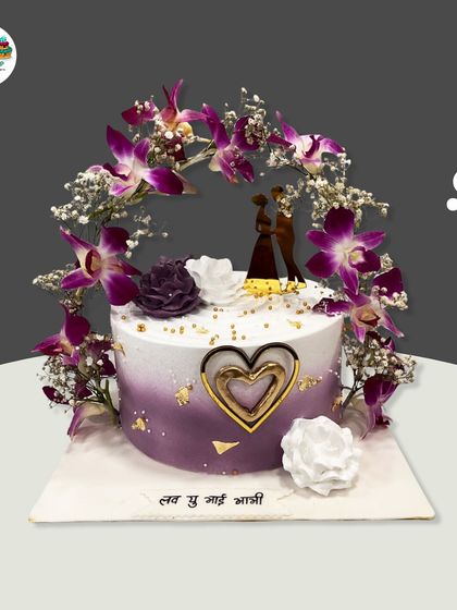 An elegant anniversary cake with a beautiful arch of fresh purple orchids and baby's breath. The purple ombre effect on the buttercream adds a touch of modern romance.