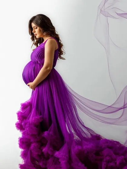 A cascade of royal purple. This gown features a pleated top and a dramatic, heavily ruffled tulle train that creates a stunning ombre effect, perfect for a high-fashion maternity look.