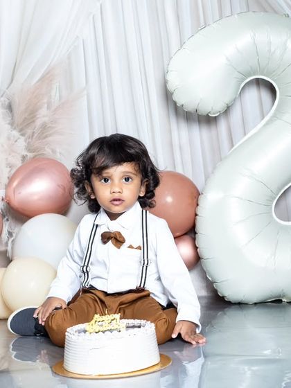 A classic portrait for a second birthday, with a large '2' balloon and a stylishly dressed toddler.