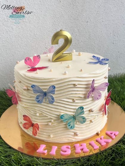 Simple cakes have our heart. This beautiful buttercream cake is decorated with a simple wave pattern and delicate, edible butterflies.
