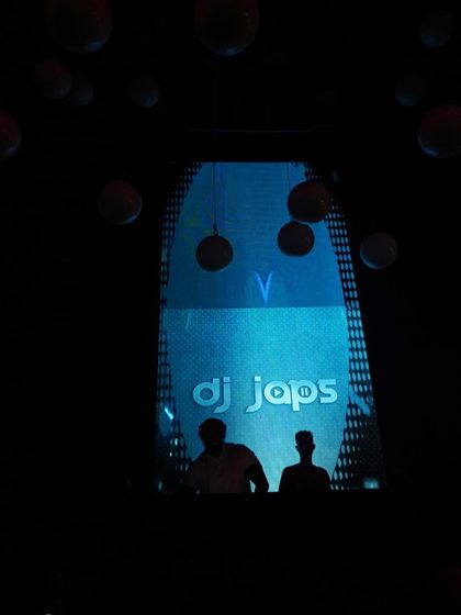 A silhouette of me and my partner against the DJ Japs logo on the screen. This is what a professional DJ duo setup looks like.