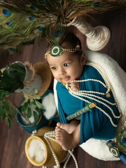 A swaddled newborn Krishna, looking peaceful and divine. Even the tiniest babies can join in the festive fun.