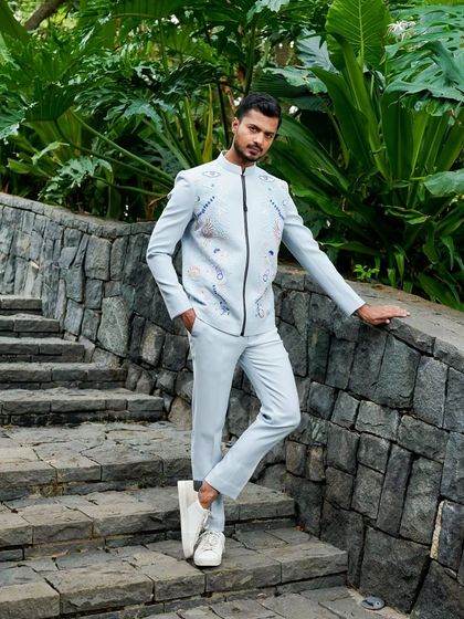 Posing on a stone staircase in a light blue embroidered jacket. This shot blends high fashion with a natural, rustic environment.