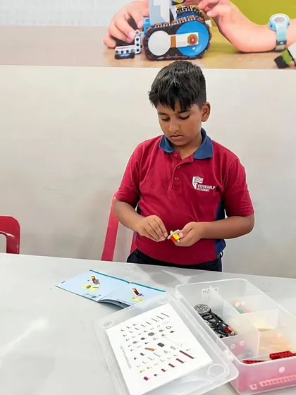 A student from Vidyashilp Academy works diligently on his project, surrounded by LEGO parts and instruction manuals.