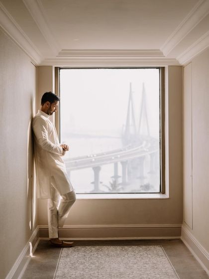 A quiet moment for the groom, looking out a window at the Mumbai sea link. This contemplative shot captures the pause and reflection before the wedding festivities begin.
