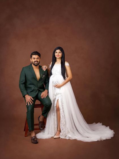 A chic and modern studio portrait of the couple. The contrast between her white lace gown and his fashion-forward green suit is striking and stylish.