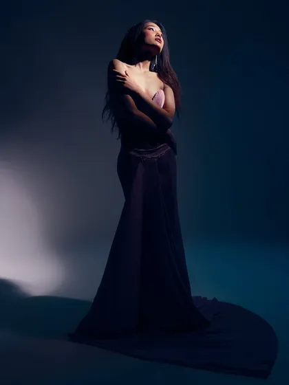 A powerful, statuesque pose where the light from above highlights the form. The sleek hair and simple makeup are essential to creating this dramatic, sculptural effect.