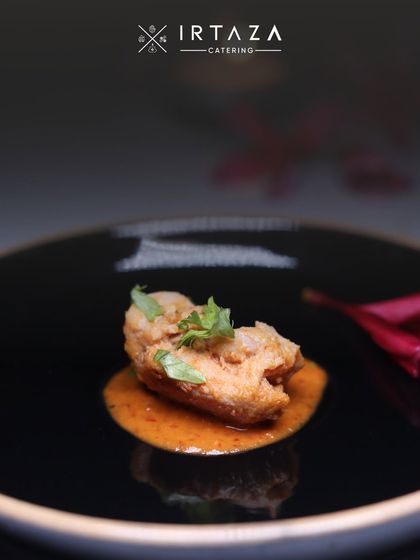 A single, perfectly cooked piece of chicken in a rich gravy, garnished with fresh herbs and served on a contemporary black plate. This image showcases my focus on flavor and fine-dining presentation, even in a single bite.