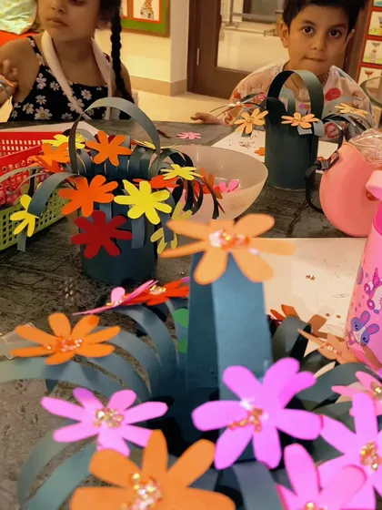 A table full of colorful paper flower baskets in progress. The studio was buzzing with love and creativity for Mother's Day.