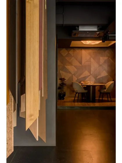 A view from the hanging veneer display towards the private discussion room. The room features a geometric wood-paneled wall, showcasing another creative application of the product.
