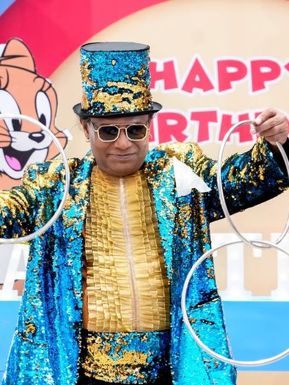A magician in a sequined jacket performs a ring trick, adding a touch of magic to the Tom & Jerry party.