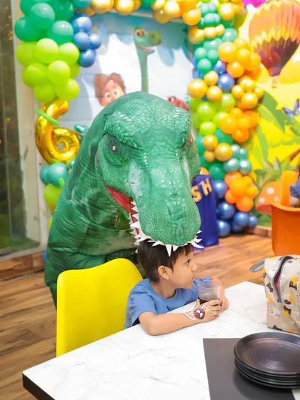 A friendly T-Rex mascot surprises a guest during a dinosaur-themed birthday party. My themed decorations and entertainment create an immersive and exciting atmosphere for everyone.