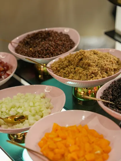 A DIY salad bar with a variety of grains and chopped vegetables in elegant pink bowls, allowing guests to create their own healthy and delicious combinations.