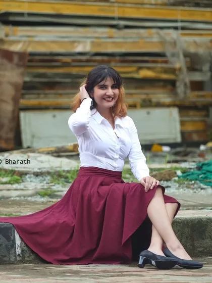 A smiling, candid-style shot of the model, seated on a step. This pose feels relaxed and natural.