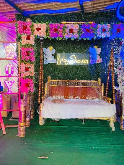 A baby shower stage illuminated with blue and pink lights, creating a festive atmosphere around the decorated swing.