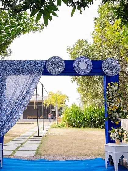 A stylish entrance gate for a blue-themed Haldi, using traditional block-printed fabric and decorative plates for a unique look.