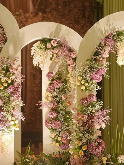 The full view of the floral arches, showcasing the asymmetrical design and the beautiful way the flowers seem to grow organically over the modern white structures.