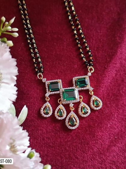 A statement mangalsutra with a pendant featuring large green stones. This piece is perfect for those who want a modern mangalsutra that is also bold and eye-catching.