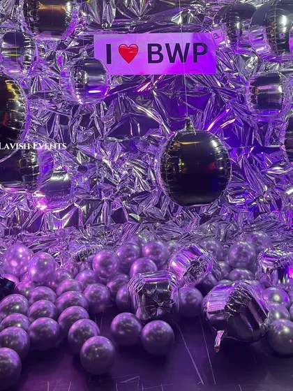 The metallic photobooth under purple light with a custom neon sign.