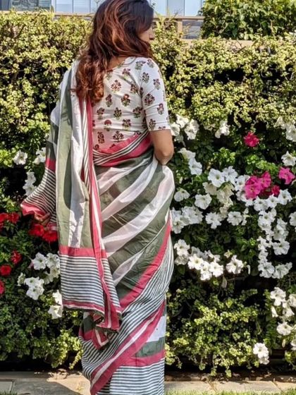 A woman stands in a garden, her striped sari perfectly complemented by a floral block-printed blouse.