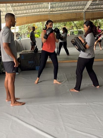 A coach watches over a pad work drill, ensuring good technique.