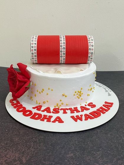This bridal-themed cake is perfect for a chooda ceremony or bridal shower. The intricate details on the fondant 'chooda' make it a truly special celebration cake.