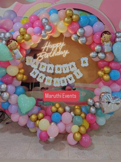 A beautiful pastel balloon ring with a neon "Happy Birthday" sign. This setup is perfect for a joint birthday celebration.