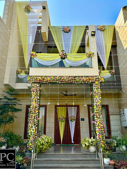 An elegant home entrance decoration. I used pastel yellow and white drapes with beautiful floral arrangements on the pillars and doorway to create a sophisticated welcome.