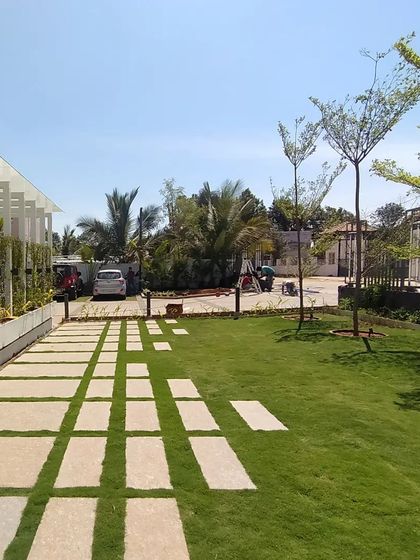 This landscape for a marketing office uses a playful pattern of stone pavers set into the lawn. The design creates a functional path that feels integrated with the green space, leading visitors towards the entrance.