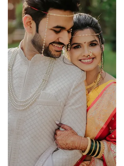 A close, happy portrait of a couple in traditional Maharashtrian wedding attire, highlighting the intricate jewelry and warm smiles.