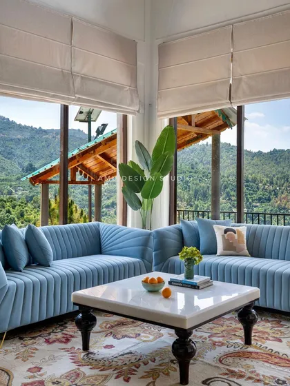 The living area is designed for comfort, with custom fluted sofas in a calming blue, set against the backdrop of the stunning mountain scenery.