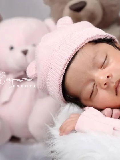 A soft and cuddly teddy bear theme is a classic choice for a newborn girl's photoshoot. The baby, wearing a pink bear-eared hat, sleeps peacefully next to a plush pink teddy bear.