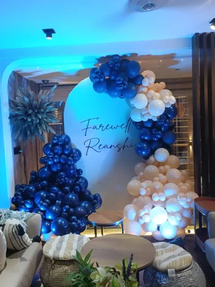 A modern and stylish farewell party decoration. I used a clean circular backdrop with the person's name, combined with a custom balloon garland in navy and cream, and accented with dried pampas grass for a contemporary look.