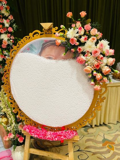 A unique and personalized welcome sign for a naming ceremony. The baby's photo is revealed from behind a layer of jasmine buds, creating a sweet and memorable detail.