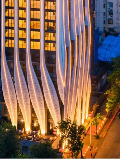 The illuminated facade from a street-level perspective, creating a dramatic and welcoming entrance experience.