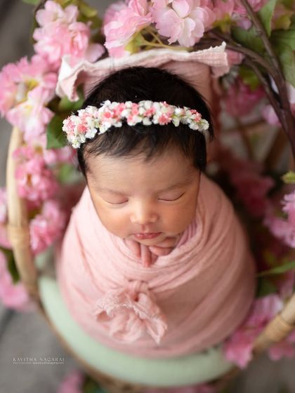 A nine-day-old angel surrounded by soft pastel pink flowers. The delicate colors and textures perfectly complement the baby's own softness and newness.