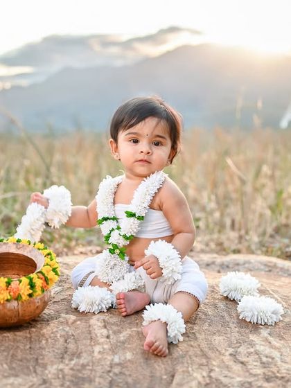 A wider shot from the outdoor session, showing the baby against a backdrop of mountains and a golden sunrise.