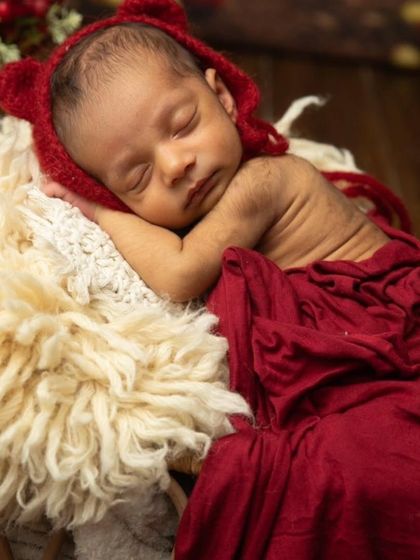 A close-up shot focusing on the baby's peaceful face, nestled on a soft, fluffy blanket in a rustic basket.