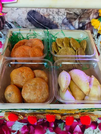 A complete Holi hamper with four different types of snacks. It includes beetroot mathri, spinach mathri, dal kachori, and gujiya, offering a perfect mix of flavors.