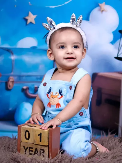 A happy one-year-old boy celebrating his birthday with our sky and teddy bear theme.