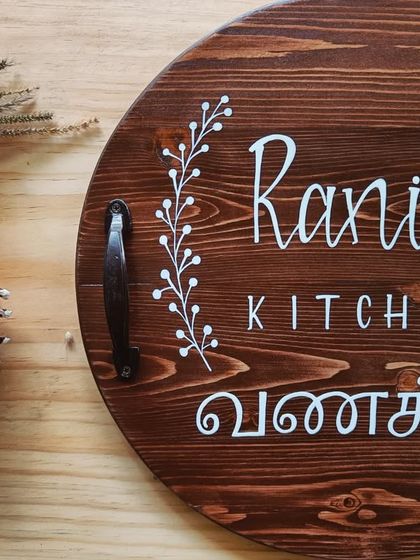 A close-up on the "Rani's Kitchen" board, focusing on the elegant calligraphy and the welcoming "Vanakkam" message.