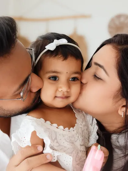 A first birthday is a celebration for the whole family. Kisses from mom and dad for the birthday girl make for an incredibly sweet and memorable family portrait.