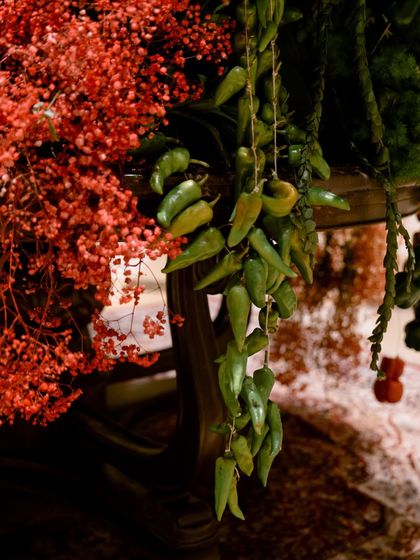 A string of green chillies hangs delicately beside sprays of red flowers. This detail showcases my philosophy of blending the botanical with the edible, creating art that is rooted in nature's diverse bounty.