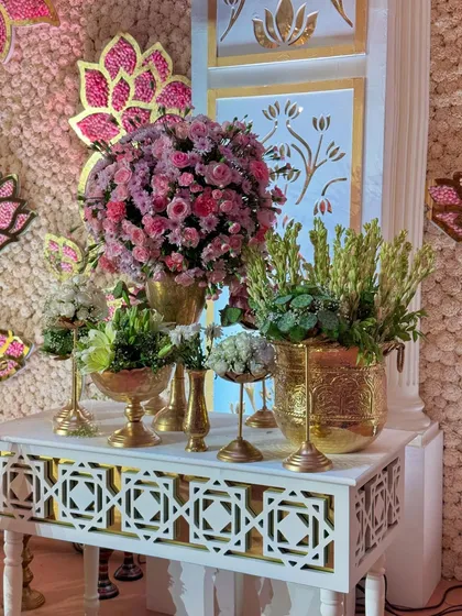 A close-up of a decor console, adorned with a variety of floral arrangements in golden vases. The intricate backdrop adds another layer of texture and luxury.