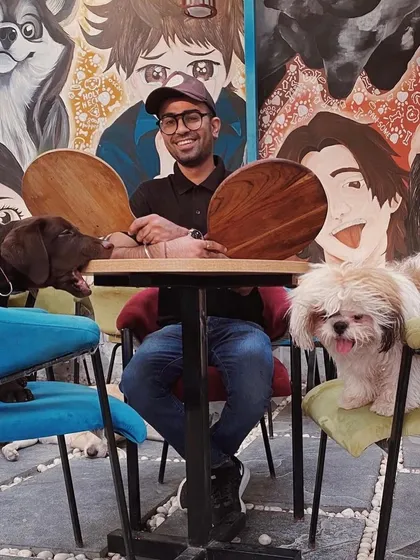 Our co-founder Nikhil enjoying a playful moment with two of our resident dogs at the table.