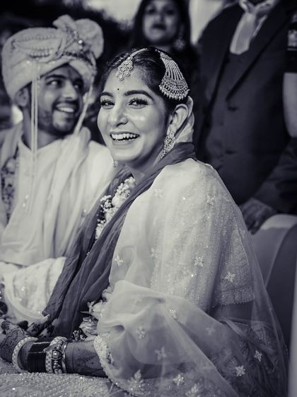 A joyful black and white candid of the bride laughing during her wedding ceremony.